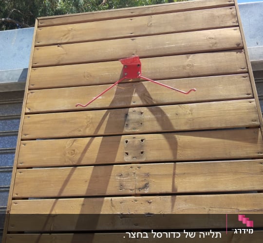מתקן מתכת אדום על קיר עץ חום
